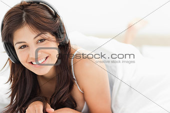 Woman lying down with a quilt over her, while listening to her h