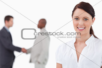 Smiling saleswoman with hand shaking colleagues behind her