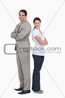 Smiling salesteam with arms folded standing back to back
