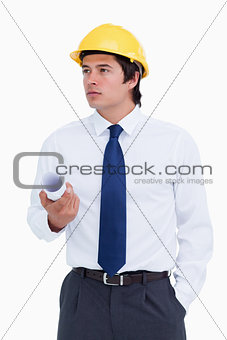 Male architect with helmet and plans looking to the side