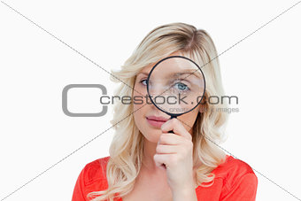 Fair-haired woman looking through a magnifying glass