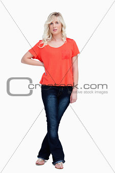 Serious fair-haired teenager standing with her legs crossed