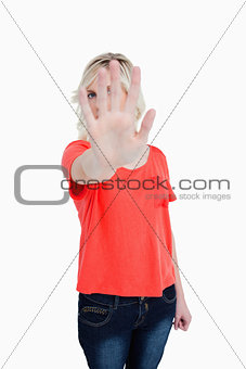 Young blonde woman trying to hide herself behind her hand