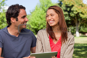 Woman looking at her friend while she is holding a tablet