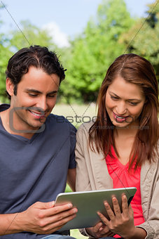 Man and his friend smiling as the watch something on a tablet