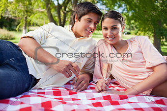 Man looking at his friend while as they lie down on a blanket wh