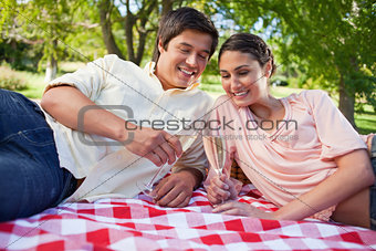 Two friends looking at glasses of champagne during a picnic