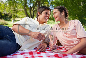 Two friends looking at each other while holding glasses during a