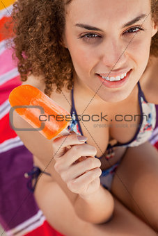 Young attractive woman in bikini holding an ice lolly while look