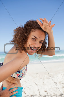 Young smiling woman placing her hand on her forehead to look at 