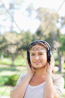 Smiling woman in the park wearing headphones