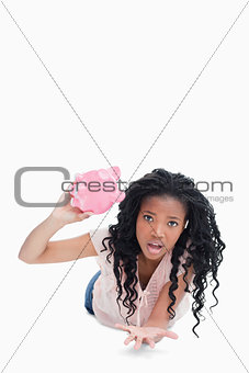 A worried young woman holding an empty piggy bank