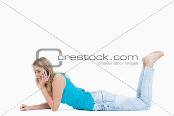 A young woman is talking on her mobile phone while lying on the 