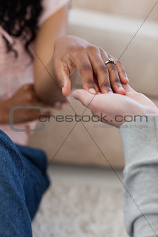 A hand with a wedding ring on it is placed in her friends hand