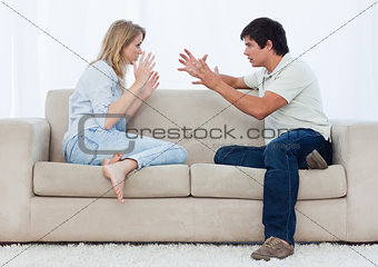 A couple sitting on a couch are having an argument