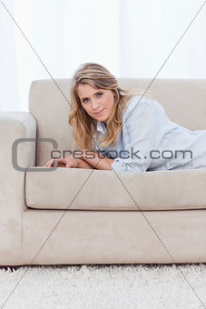 A woman lying on a couch is leaning on her elbows