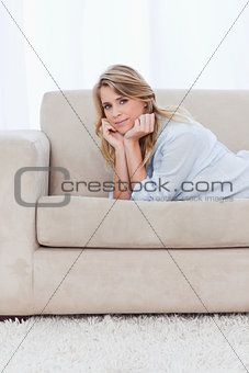 A woman looking at the camera is resting her head on her hands