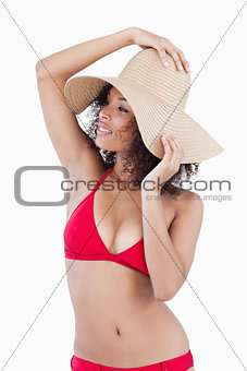 Attractive young woman looking away while holding her hat