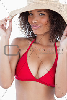Young woman holding her hat brim while looking at the camera