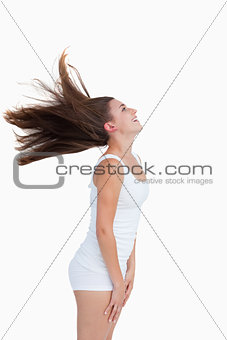 Side view of a young woman standing while flipping her hair