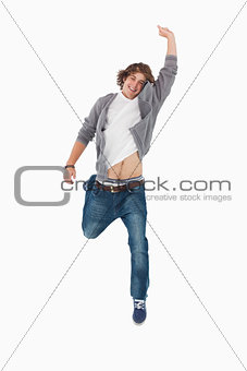 Male student posing by jumping with a raised arm