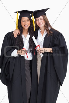 Two women embracing each other after they graduated from univers