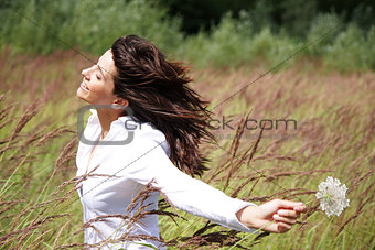 Beautiful woman outside, with wind in her face and a flower