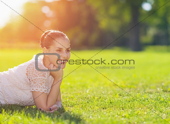 Smiling girl laying on meadow and looking on copy space