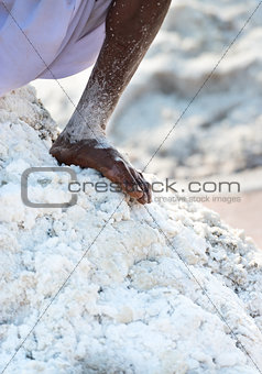 Bare worker foot salt in salt farm 