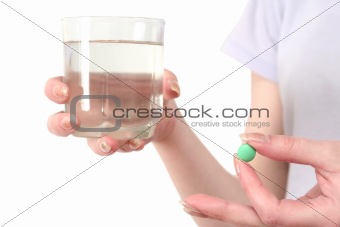 Green tablet and glass of water in hands