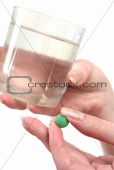 Green tablet and glass of water in hands