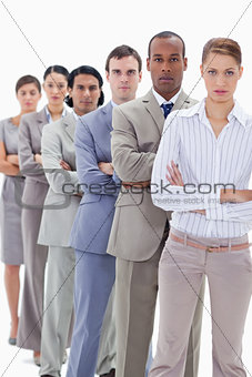 Serious workmates dressed in suits crossing their arms in a sing