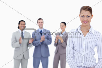 Close-up of a woman smiling with business people applauding