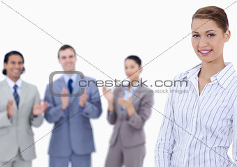 Close-up of a woman smiling with business people applauding whil