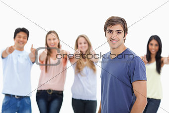Man smiling with people approving behind him