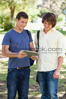 Two smiling male students with a touch pad