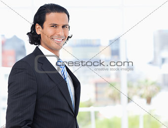 Young executive proudly standing in front of a window