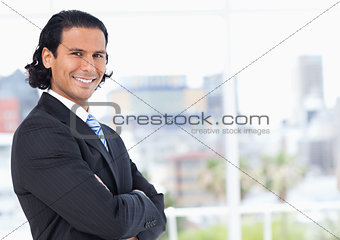 Executive standing upright in front of a window and looking towa