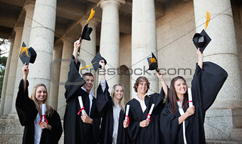 Smiling graduates holding up their hats