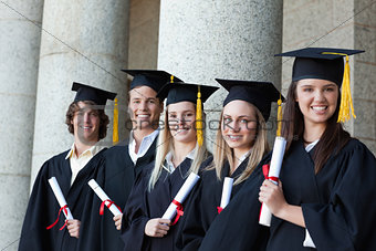 Smiling graduates posing in single line