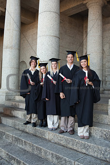 Laughing graduates posing the thumb-up