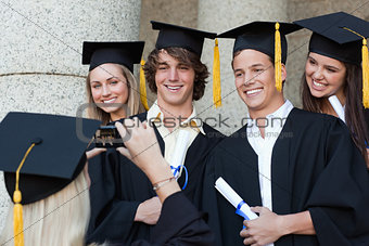 Close-up of a graduate taking a picture of her friend