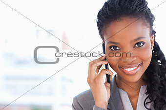 Young smiling businesswoman looking ahead while talking on a pho