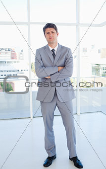 Businessman standing upright in front of a bright window and cro