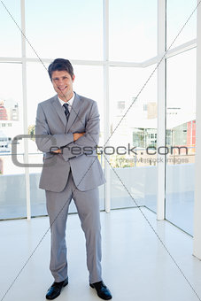 Laughing businessman crossing his arms while standing in a well 