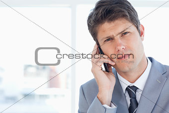 Young executive seriously talking on the phone in front of a win