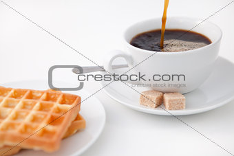 Waffles sugar and a cup of coffee on white plate