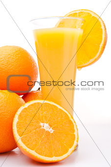 Pile of oranges near a glass of orange juice