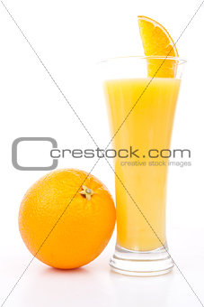 Orange placed next to a glass of orange juice