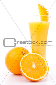 One orange and a half next to a glass of orange juice